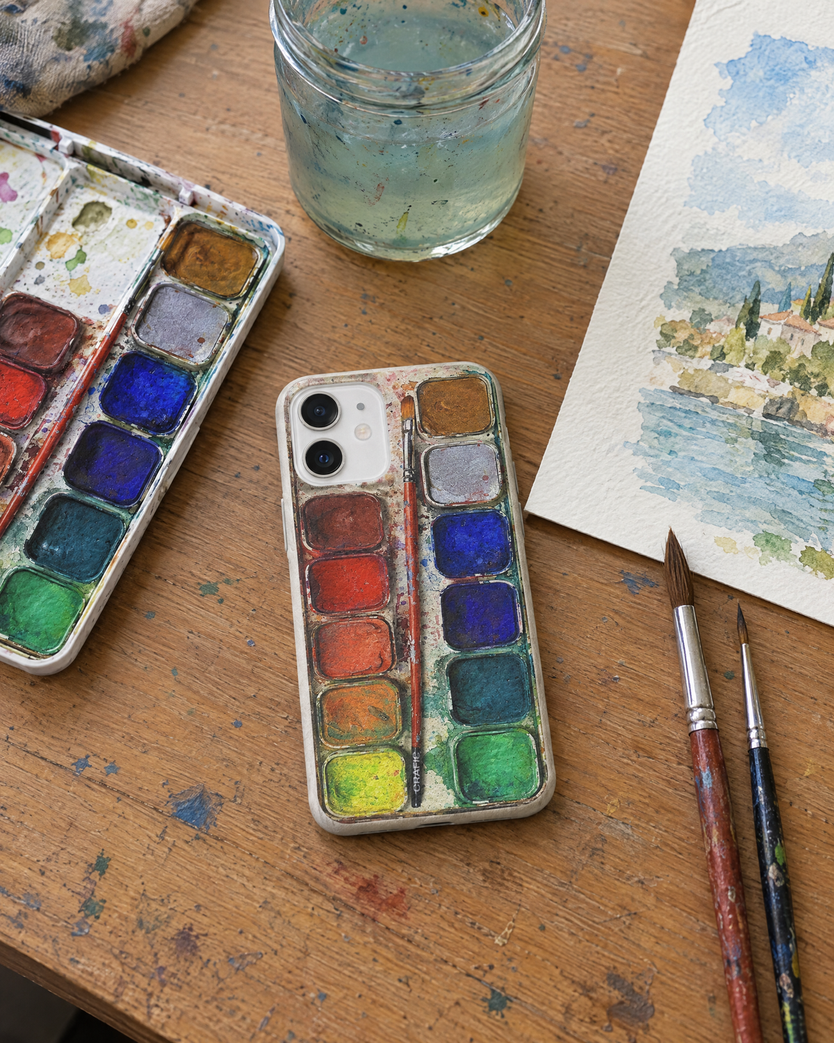 The watercolor case on a painter's desk next to a real paint tin